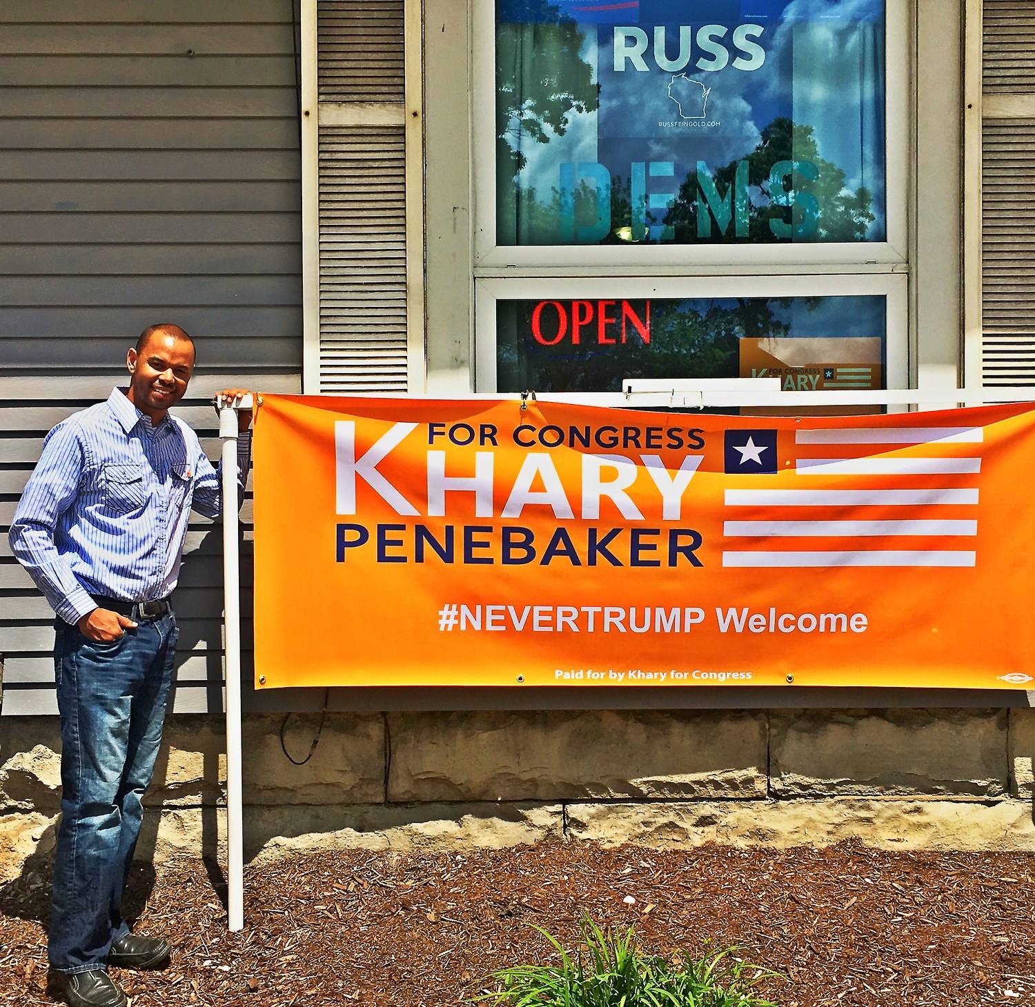Khary beside an orange For Congress Khary Penebaker banner